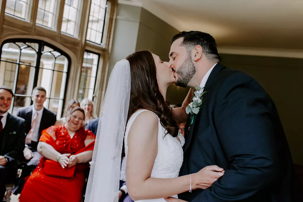 Couple’s first kiss at Coombe Lodge wedding ceremony surrounded by family and friends