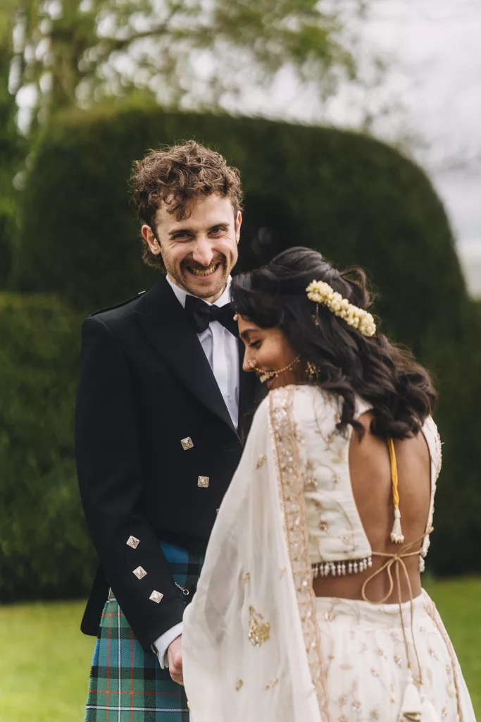 A groom in traditional Irish tartan marries a bride in traditional Tamil wedding clothing in an outdoor celebrant wedding ceremony